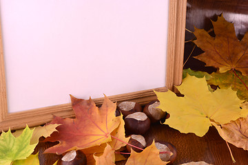 Image showing autumn chestnuts on wooden background and blank paper card