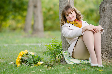 Image showing The girl at the tree with a bouquet of yellow roses