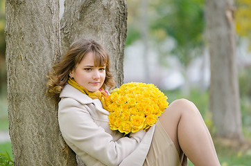 Image showing Cute little girl with yellow roses against a tree