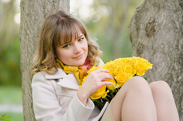 Image showing Sad girl with yellow roses, sitting in a tree