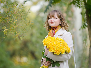 Image showing Girl on nature with a bouquet of yellow roses