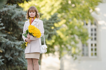 Image showing Cute little girl with a bouquet of yellow roses walks in the park