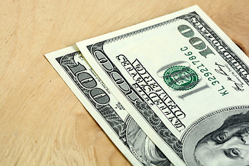 Image showing Close-up of a 100 dollars banknotes on wooden background