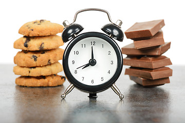 Image showing Black alarm clock and sweets