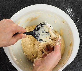 Image showing Person handling a sticky dough with black spatula in white plast