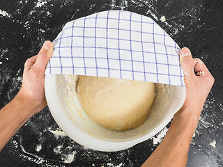 Image showing Person covering a dough for proving in a bowl on black table