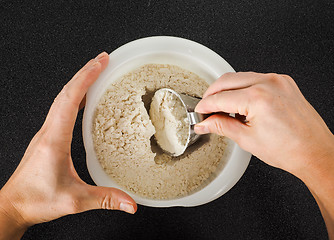 Image showing Person using a measurement tool in a bowl of wheat flour