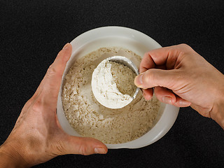 Image showing Person using a measurement tool in a bowl of wheat flour