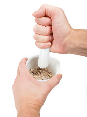 Image showing Person crushing brown sugar cubes in a white marble mortar