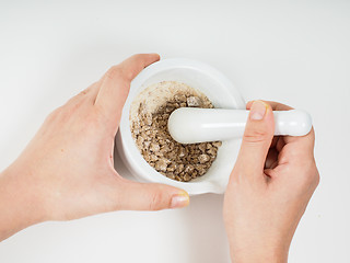 Image showing Person crushing brown sugar in a white marble mortar