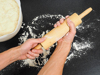 Image showing Person preparing a wooden rolling pin with wheat flour before wo