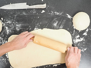 Image showing Person handling a dough with a rolling pin floured black table 