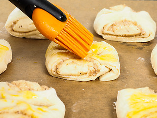 Image showing Closeup of person glazing plaited baked goods with egg wash