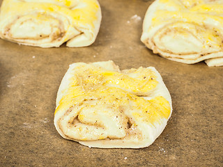 Image showing Plaited cinnamon rolls on baking paper with egg wash