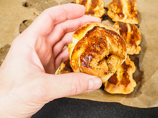 Image showing Person holding a cinnamon bun over plaited buns