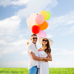 Image showing smiling couple with air balloons outdoors