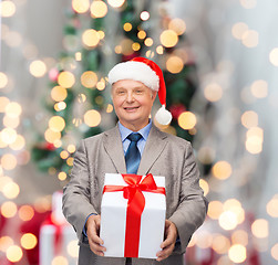 Image showing smiling man in suit and santa helper hat with gift