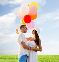 Image showing smiling couple with air balloons outdoors