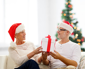 Image showing happy senior couple in santa hats with gift box