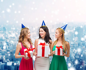 Image showing smiling women in party caps with gift boxes