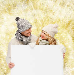 Image showing smiling couple in winter clothes with white board