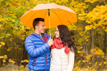 Image showing smiling couple with umbrella in autumn park