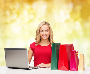 Image showing smiling woman in red shirt with gifts and laptop