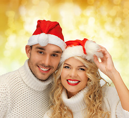 Image showing smiling couple in sweaters and santa helper hats