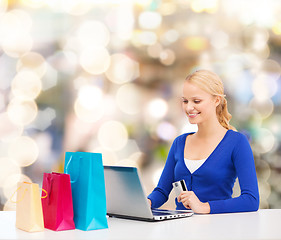 Image showing smiling woman with credit card and laptop