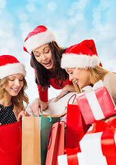 Image showing smiling young women in santa hats with gifts