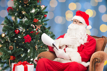 Image showing man in costume of santa claus with notepad