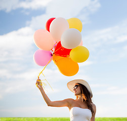 Image showing smiling young woman in sunglasses with balloons