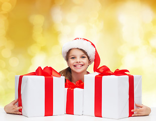 Image showing smiling girl in santa helper hat with gift boxes