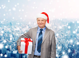 Image showing smiling man in suit and santa helper hat with gift