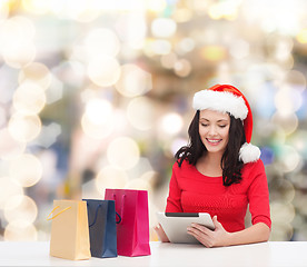 Image showing smiling woman in santa hat with bags and tablet pc