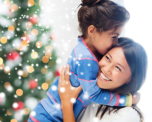 Image showing smiling little girl and mother hugging indoors