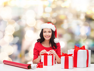 Image showing smiling woman in santa helper hats packing gifts