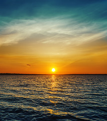 Image showing orange sunset over dark water