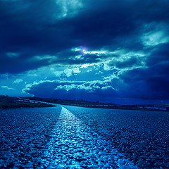 Image showing low dramatic clouds over asphalt road in dark blue moonlight