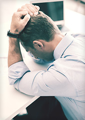 Image showing stressed businessman with papers at work