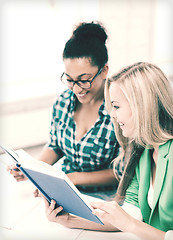 Image showing smiling student girls reading book at school