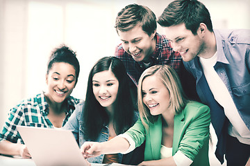 Image showing smiling students looking at laptop at school