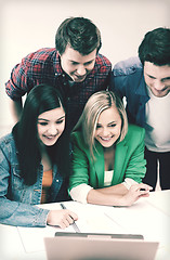 Image showing smiling students looking at laptop at school