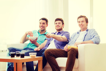 Image showing smiling friends with remote control at home