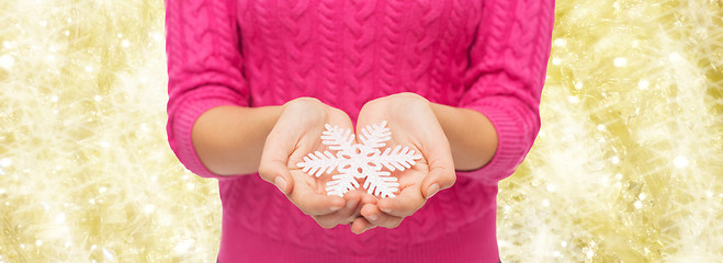 Image showing close up of woman in sweater holding snowflake