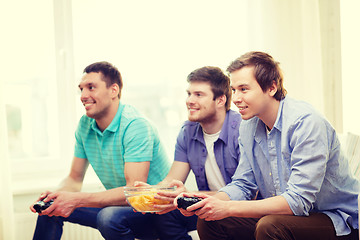 Image showing smiling friends playing video games at home