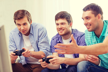 Image showing smiling friends playing video games at home
