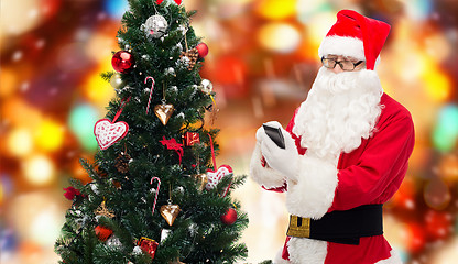 Image showing santa claus with smartphone and christmas tree