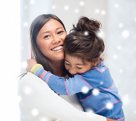 Image showing smiling little girl and mother hugging indoors