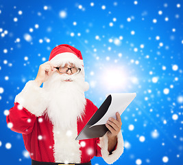 Image showing man in costume of santa claus with notepad